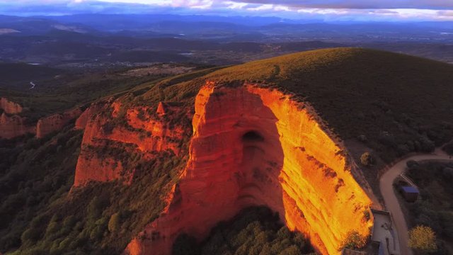 Breathtaking golden sunset over the Las Medulas, a historic gold-mining site, with a balcony at the end of a visitable tunnel, Ponferrada, El Bierzo, Leon, Spain. Aerial wide parallax shot