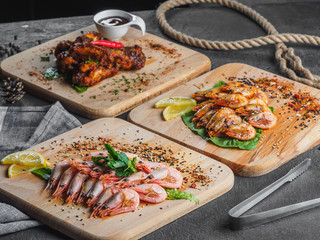 Shrimps with lemon and fried chicken wings on wooden board