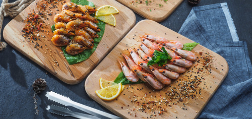 Raw and fried shrimps with lemon on wooden board