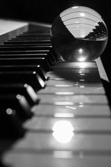 Black and white photo of a glass sphere refracting keys of a piano