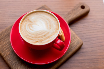 coffee-break. Red cup of cappuccino with beautiful latte art on old wooden background. Latte art coffee.aroma coffee in red ceramic cup. Copy space.wood table in cafe, restaurant
