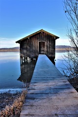 Idyllic sunny winter day at the bavarian Lake Kochelsee (Lake Kochel) at Kochel am See. View to the beautiful wooden boathuts