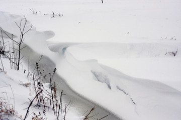 Extreme Schneefälle gefrieren Bäche, Flüsse und Seen und verzaubern sie in idyllische Winterlandschaften für Wintersport wie Schlittenfahren, Skifahren und Rodeln im tiefen Schnee mit Schneeflocken