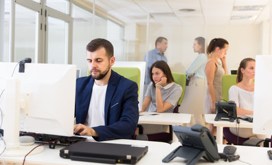 Focused successful male working at laptop in busy modern office