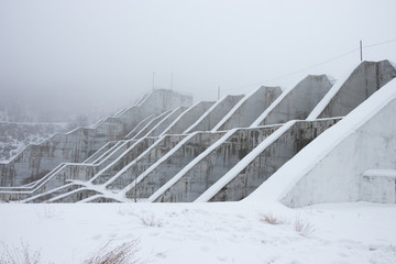 dam in the snow in the mountains with fog