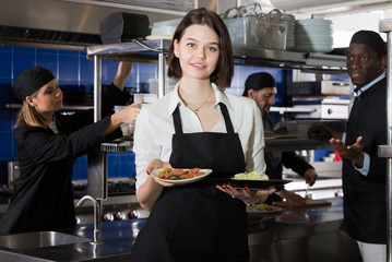 Fototapeta na wymiar Waitress holding meals in restaurant kitchen