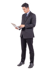 Young business man in suit standing with serious face looking and working on laptop isolated on white background, copy space and business concept.