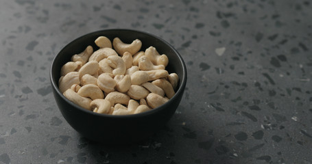 cashew nuts in black bowl on terrazzo countertop