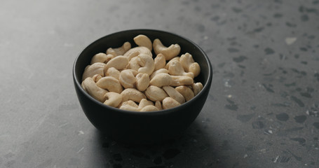cashew nuts in black bowl on terrazzo countertop
