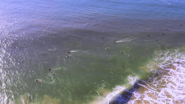 Surfers floating on the surfing boards waiting for the Supertubes wave, Supertubos beach, Peniche, Portugal, Aerial dolly out wide angle shot