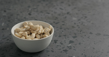 cashew nuts from white bowl on terrazzo countertop