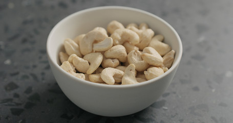 cashew nuts from white bowl on terrazzo countertop