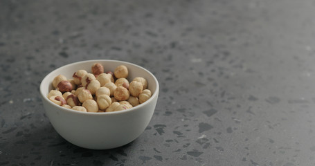 roasted hazelnuts in white bowl on terrazzo countertop