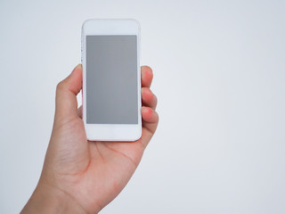 Hand holding smartphone with white wall background