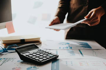 Business man analysis financial report on working desk and couting with calculator