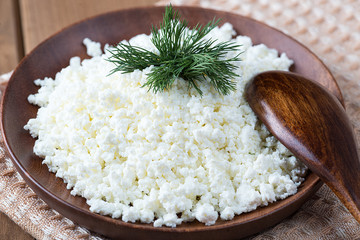 Cottage cheese in a wooden plate on a wooden table