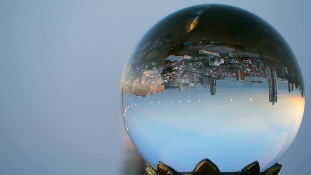 The city is upside down when the sunsets in a crystal ball due to the reflection of light