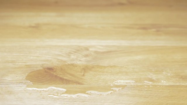Close up of a hand holding a glass of water from a laminate wood floor