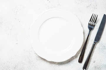 White plate and cutlery on white background.