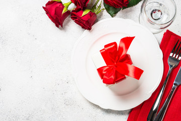 Romantic holiday table setting with plate, roses and present.