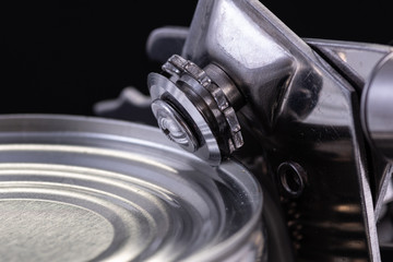 a handmade can opener from Finland next to a can on a black background