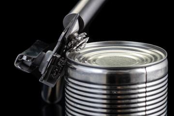 a handmade can opener from Finland next to a can on a black background