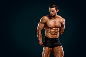 Fototapeta na wymiar Bodybuilder Posing and Flexing Muscles. Studio Shot