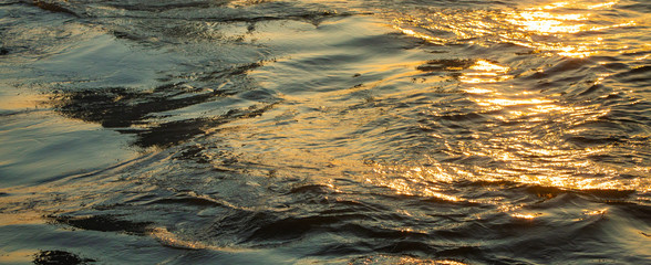 golden water wave reflection in sunset.Gold water texture.