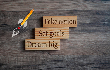 Wooden blocks with business terms Dream Big, set goals and take action on wooden background