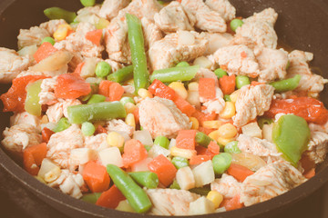 Roasted fat chicken pieces with vegetable mixture in pan.
