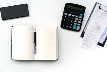 Office work table with bill, mobile phone, notebook and calculator on white table , Top view, copy space for text message