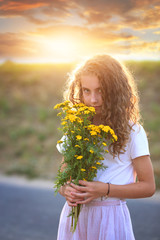 young girl smells wildflowers