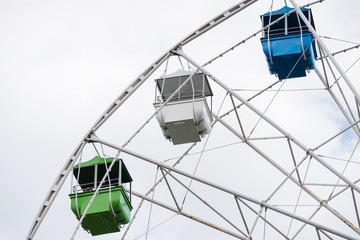 Carousel ferris wheel with colored cabins for children and adults to ride on day off.