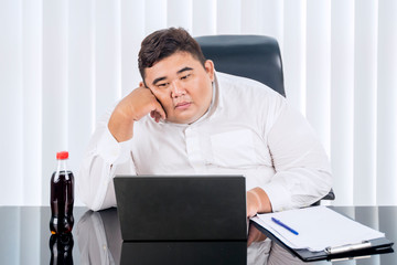 Fat Asian businessman working at his laptop busily