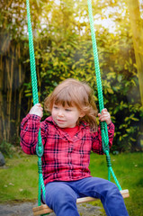 adorable little girl playing in the garden with her swing