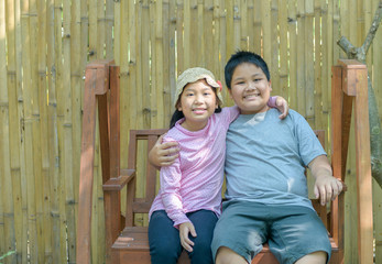 Happy Brother and sister smile and sit on swing.