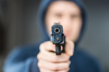 Crime or robbery concept: Man with black gun is aiming with his weapon