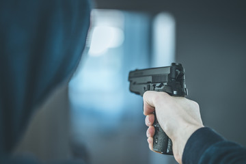 Crime or robbery concept: Man with black gun is aiming with his weapon