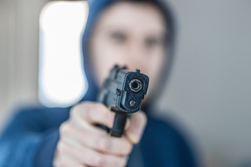 Crime or robbery concept: Man with black gun is aiming with his weapon