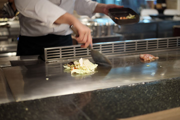 Japanese chef cooking meat in teppanyaki restaurant