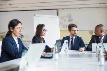 Group of confident managers communicating during meeting. Focused young business people talking during briefing. Business meeting concept