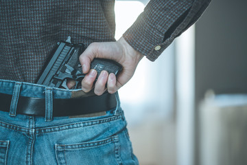 Police undercover weapon concept: Man is holding hidden short gun in his hand
