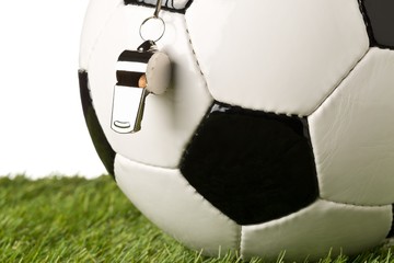Single black and white soccer sports ball with referee whistle close up with selective focus on...