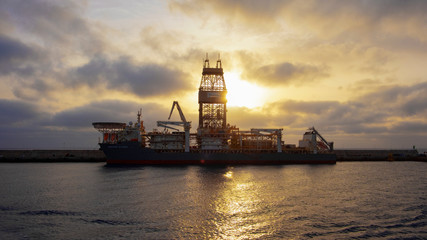 Fototapeta na wymiar Sunrise over a docked drill ship named Deepwater Mykonos sailing under the flag of Liberia and managed by Transocean, Puerto de las Palmas, Gran Canaria, Canary Islands, Spain