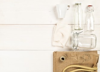 Zero waste or waste free shopping utensils with burlap bag, glass bottles and cotton bag on white wooden table background
