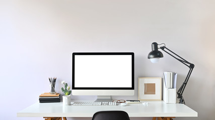 Photo of Contemporary Workspace..White blank screen monitor on modern working desk. Equipment on table. Modern office concept.