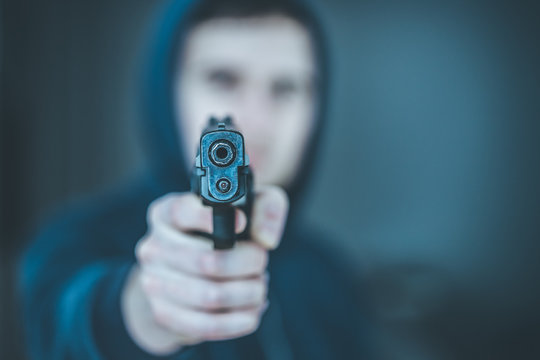 Crime or robbery concept: Man with black gun is aiming with his weapon