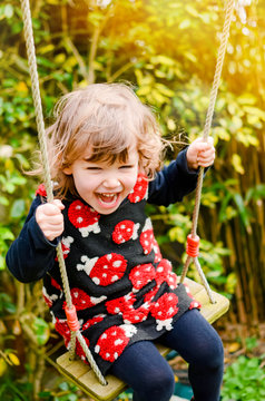 adorable little girl playing in the garden with her swing