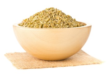 Heap of uncooked, raw freekeh or firik, roasted wheat grain, in wooden bowl over white