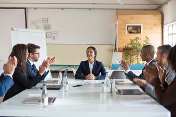 Subordinates applauding successful Asian speaker. Group of smiling business people during morning briefing. Business meeting concept